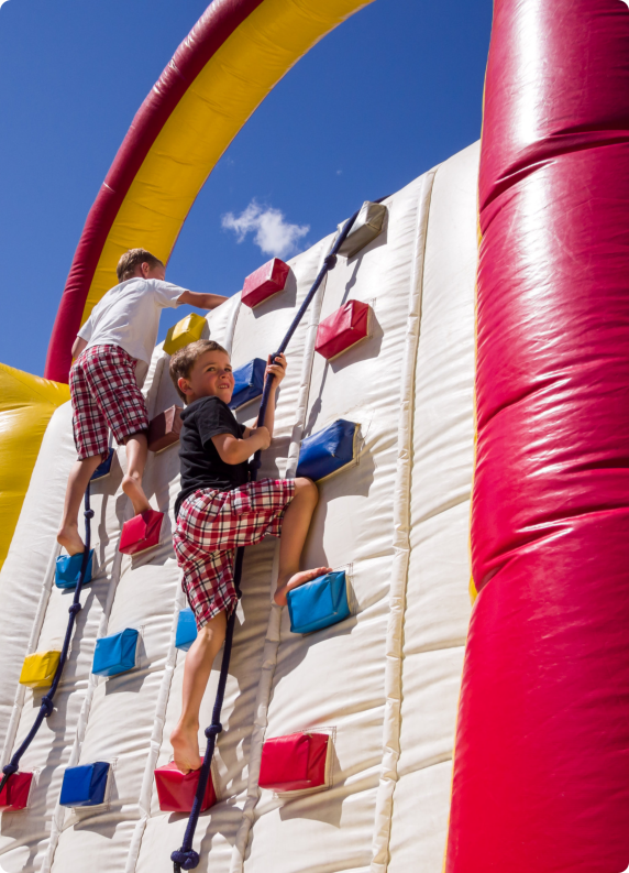 Two children climbing on a colorful inflatable climbing wall