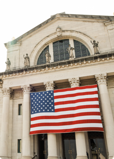 A large American flag is displayed prominently outside a building
