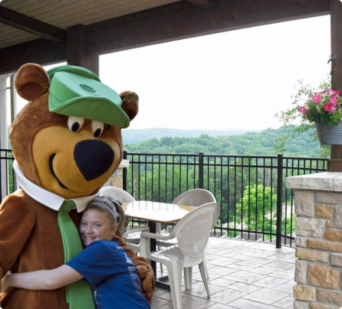 A young girl joyfully hugs a large teddy bear