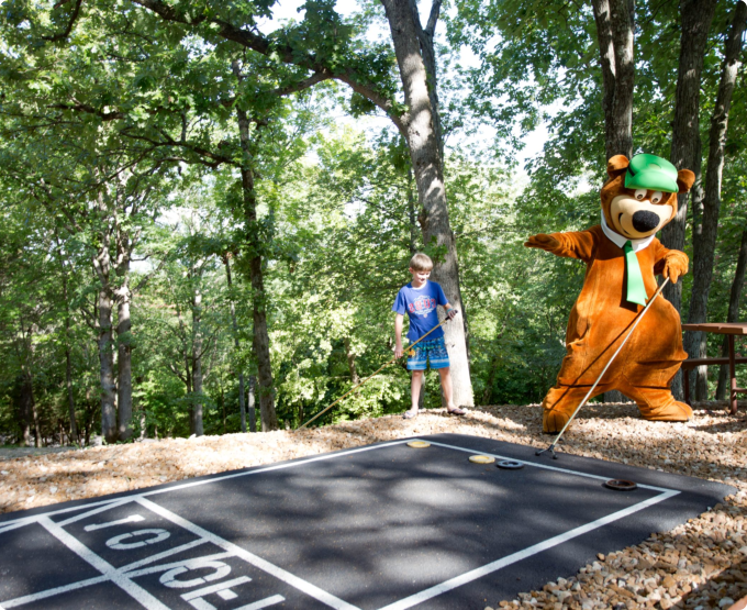 A man dressed in a bear costume swings a golf club