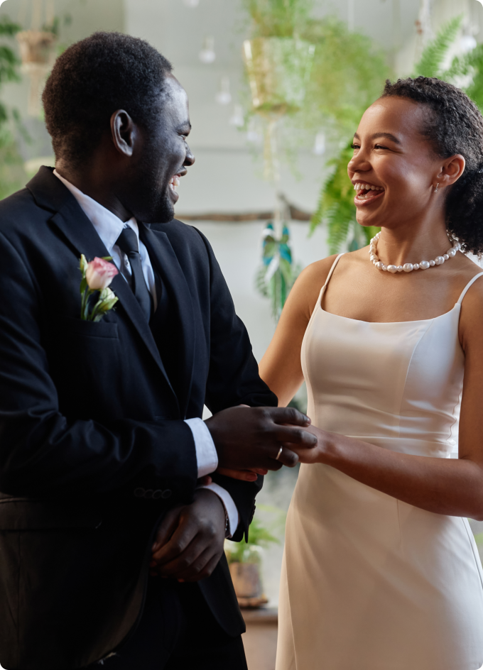 A man and woman in wedding attire smiling at each other