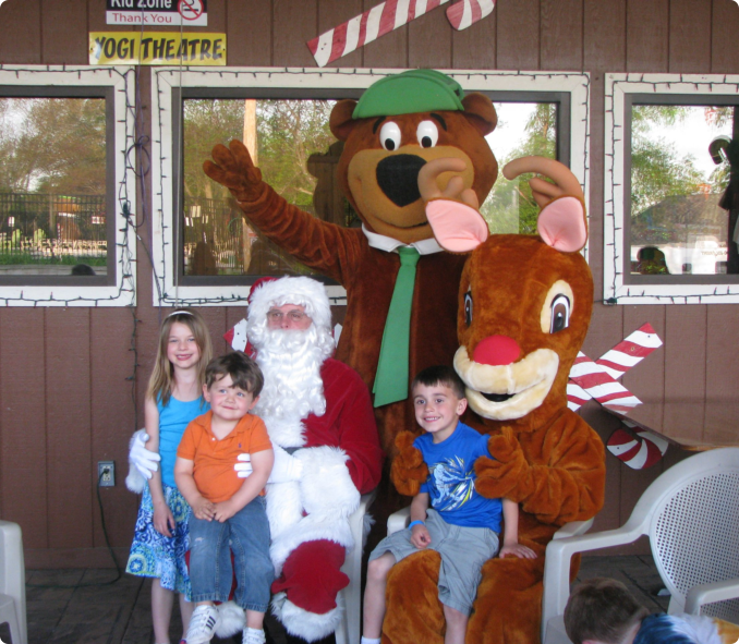 A group of smiling children poses with a colorful mascot